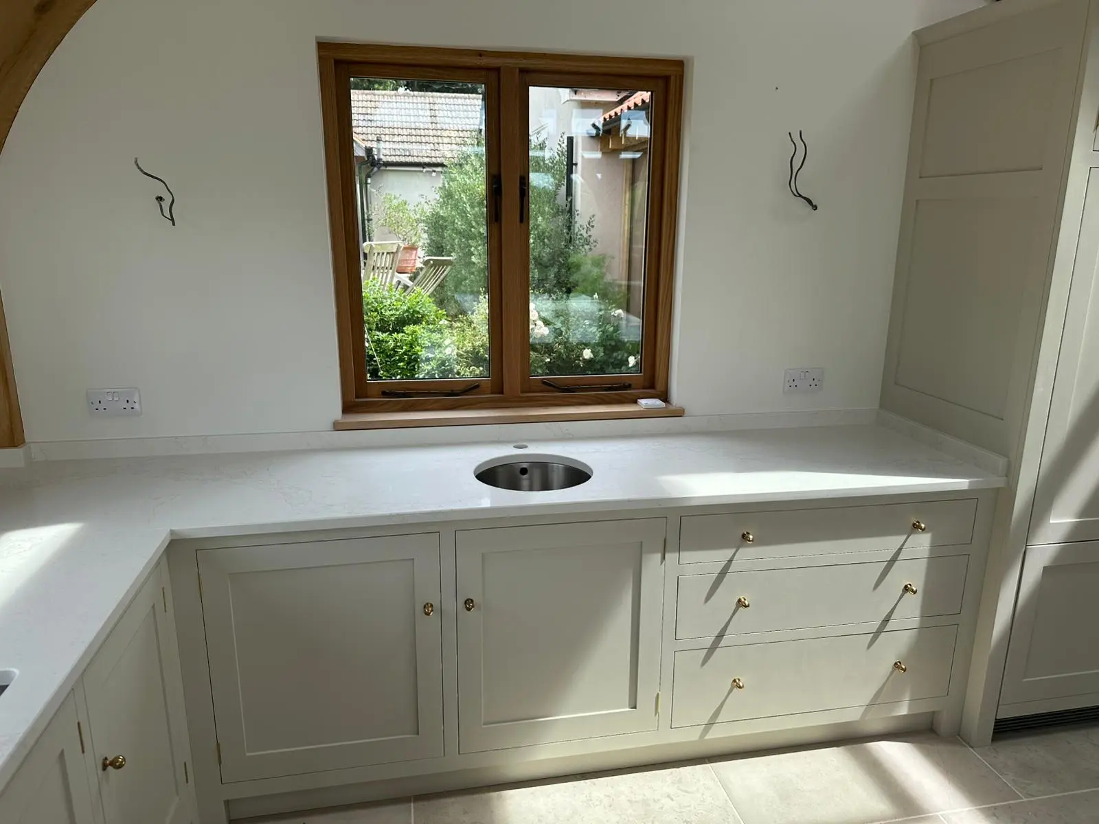 Quartz worktop fitted in a shaker kitchen with an oak framed window