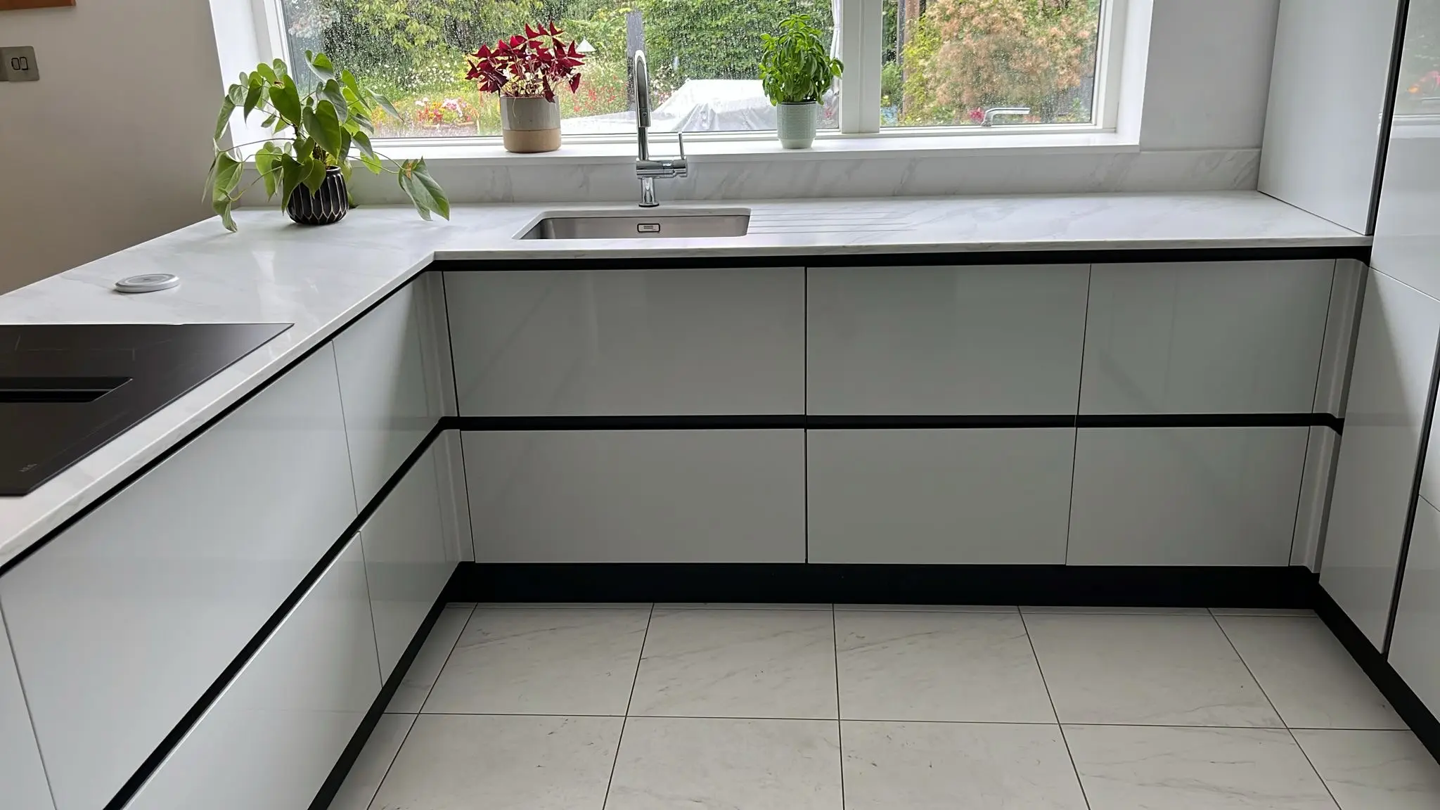 White engineered quartz worktop and windowsill in a modern fitted kitchen