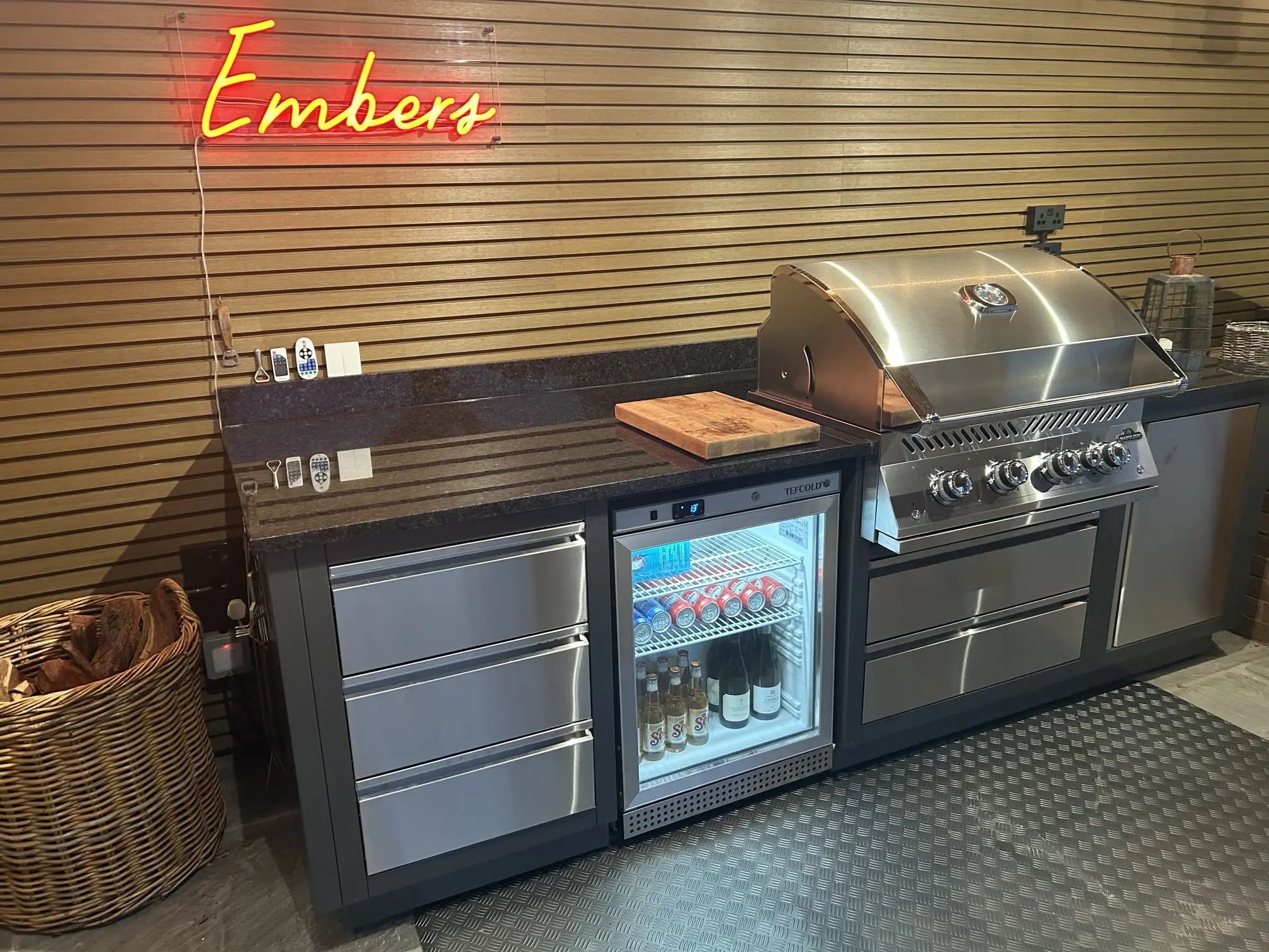 Outdoor kitchen with a dark granite worktop, built-in barbecue and drinks fridge
